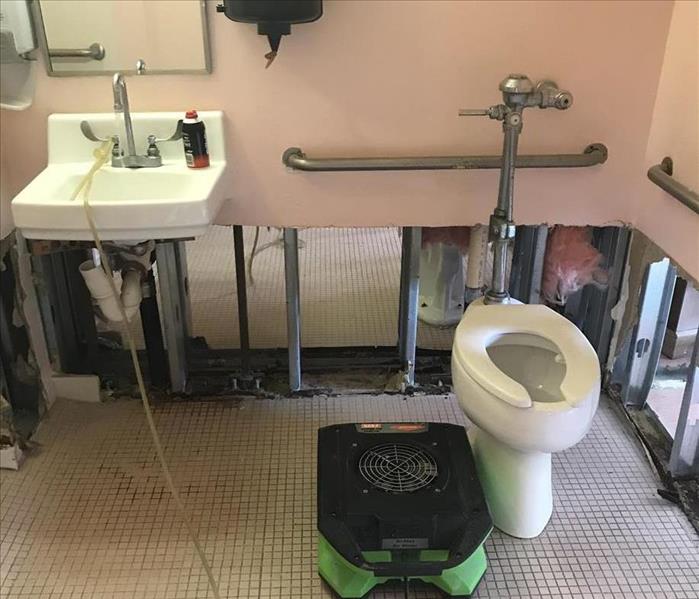 A commercial bathroom, with SERVPRO equipment on the floor. 